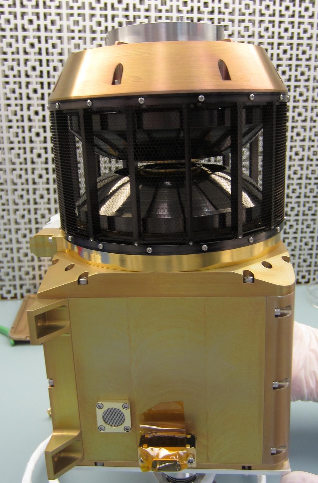 This image shows the wind analyzer instrument box that is yellow metal at the bottom, the top is a circular black cylinder. The whole instrument is the size of a shoebox.
