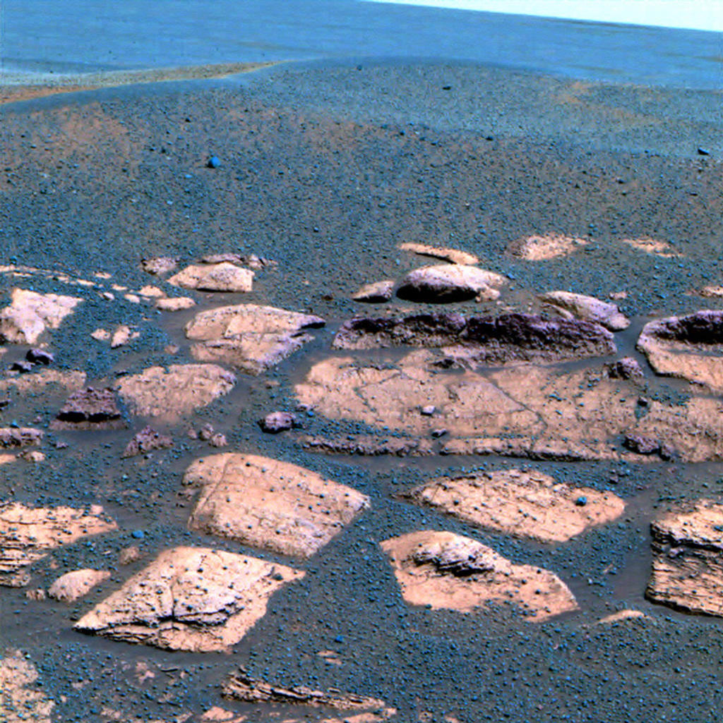 Esta imagem falsa cor sugere que as planícies além da pequena cratera onde a Mars Exploration Rover Opportunity agora se senta estão cheios com o mesmo material cinza escuro encontrados dentro da cratera na forma de esférulas ou "blueberries".