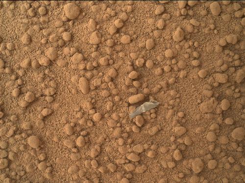 This image from the Mars Hand Lens Imager (MAHLI) camera on NASA's Mars rover Curiosity shows a small bright object on the ground beside the rover at the "Rocknest" site.