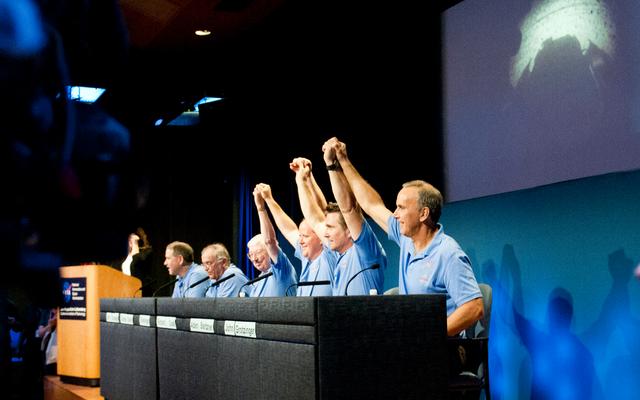 Mars Science Laboratory mission scientists, flight controllers, managers and administrators raise their hands to a cheering crowd at a news conference following the successful landing of NASA's Curiosity rover on Mars.