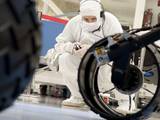 A test operator in clean-room garb observes rolling of the wheels during the first drive test of NASA's Curiosity rover, on July 23, 2010.