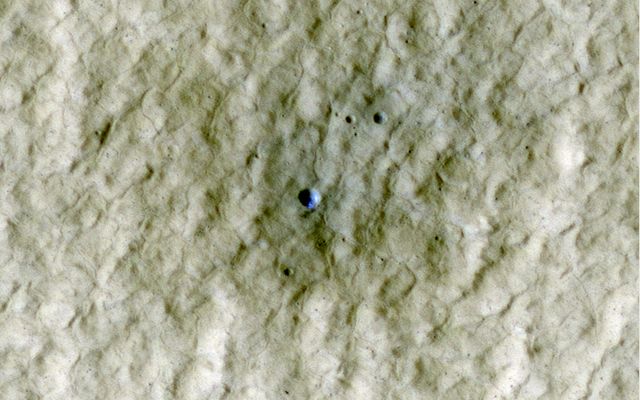 At the center of this view of an area of mid-latitude northern Mars, a fresh crater about 6 meters (20 feet) in diameter holds an exposure of bright material, blue in this false-color image.