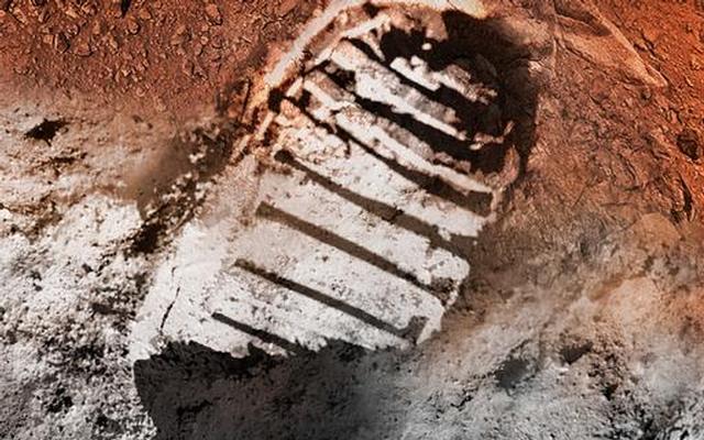 An artist's concept showing an astronaut boot print.  Half the boot print is on orange soil, while the other on gray.