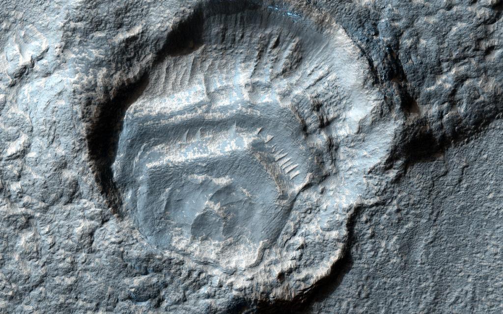 This image features a gray crater in the middle with a deep hole that looks like it was struck multiple times by a Martian meteorite.