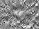 A small impact crater on Mars named Gratteri, 4.3 miles (6.9 km) wide, lies at the center of large dark streaks.