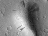 This Mars Global Surveyor (MGS) Mars Orbiter Camera (MOC) image shows dark slope streaks coming down the slopes of a knob in western Amazonis Planitia. All of the surfaces in this image are mantled by dust. On the slopes, mass movement of dry dust has created the streaks.