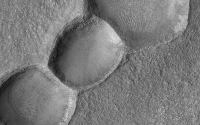 This Mars Global Surveyor (MGS) Mars Orbiter Camera (MOC) image shows a 1.5 meters per pixel (~5 ft/pixel) view of three aligned meteor impact craters on the floor of a much larger crater in the Noachis Terra region. The craters may have formed together from a single event in which the impactor (the meteor) was broken into three pieces.