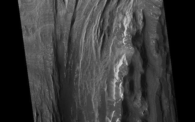 This HiRISE image shows a portion of interior layered deposits (ILD) in Juventae Chasma. Juventae Chasma is a large depression near the equatorial canyon system Valles Marineris. The scene is along the top of a mound of layered deposits on the floor of Juventae Chasma. Dunes are seen in the low-lying, darker regions. Very fine layers are also seen (see subimage, approximately 1 km across). Understanding what kinds of materials formed the layers, how they were set in place, and how they have evolved will provide insight into Martian geologic history.