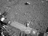 This image shows a close-up of track marks from the first test drive of NASA's Curiosity rover. The rover's arm is visible in the foreground.