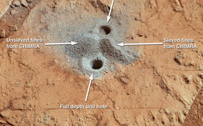 This image shows the first holes into rock drilled by NASA's Mars rover Curiosity, with drill tailings around the holes plus piles of powdered rock collected from the deeper hole and later discarded after other portions of the sample had been delivered to analytical instruments inside the rover.