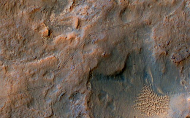 Two parallel tracks left by the wheels of NASA's Curiosity Mars rover cross rugged ground in this portion of a Dec. 11, 2013, observation by the High Resolution Imaging Science Experiment (HiRISE) camera on NASA's Mars Reconnaissance Orbiter.
