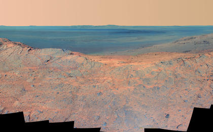 This May 14, 2014, scene from the Pancam on NASA's Mars Exploration Rover Opportunity catches "Pillinger Point," on the western rim of Endeavour Crater, in the foreground and the crater's eastern rim on the horizon. The scene's false color makes differences in surface materials more easily visible.