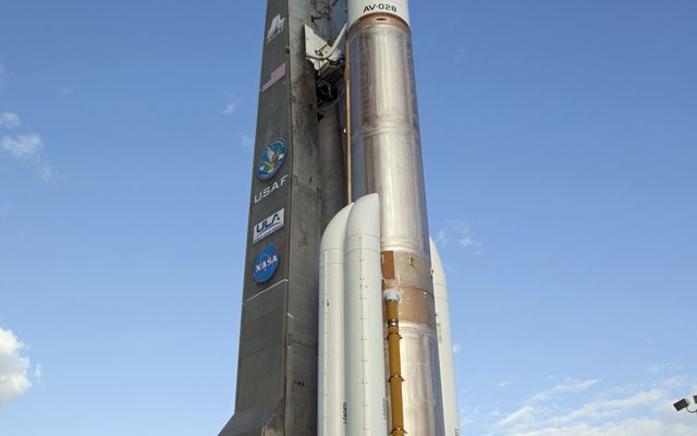 On Cape Canaveral Air Force Station in Florida, the 197-foot-tall United Launch Alliance Atlas V rocket is backdropped by a bright blue sky as the vehicle rolls from the Vertical Integration Facility (VIF) to the launch pad at Space Launch Complex 41.