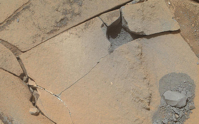 This Jan. 13, 2015, view from the Mars Hand Lens Imager on NASA's Curiosity Mars rover shows outcomes of a mini-drill test to assess whether the "Mojave" rock is appropriate for full-depth drilling to collect a sample. Cracking of the rock has made freshly exposed surfaces available for inspection.