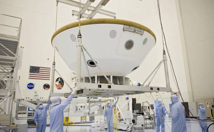 At the Payload Hazardous Servicing Facility at NASA's Kennedy Space Center in Florida, technicians using an overhead crane, move the aeroshell, a component of NASA's Mars Science Laboratory (MSL), back to a work stand after a spin and balance test.
