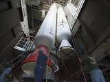 Inside the Vertical Integration Facility at Space Launch Complex 41 on Cape Canaveral Air Force Station in Florida, technicians using an overhead crane guide the final solid rocket motor into position for mating to the first stage of a United Launch Alliance Atlas V rocket.