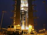 The Atlas V rocket set to launch NASA's Mars Science Laboratory (MSL) mission is illuminated inside the Vertical Integration Facility at Space Launch Complex 41, where employees have gathered to hoist the spacecraft's multi-mission radioisotope thermoelectric generator (MMRTG).