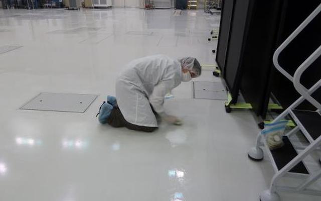 A microbiologist collects a swab sample from the floor of a spacecraft assembly clean room at NASA's Jet Propulsion Laboratory.