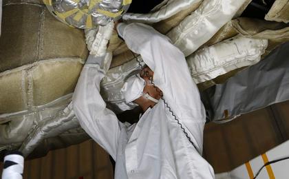 An engineer works on the Parachute Deployment Device of the Low Density Supersonic Decelerator test vehicle in this image taken at the Missile Assembly Building at the US Navy's Pacific Missile Range Facility in Kaua'i, Hawaii.