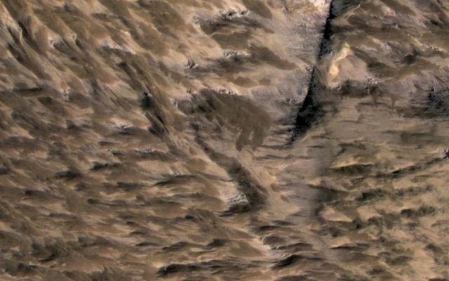 This April 6, 2014, image from the High Resolution Imaging Science Experiment (HiRISE) camera on NASA's Mars Reconnaissance Orbiter shows numerous landslides in the vicinity of where an impact crater was excavated in March 2012.