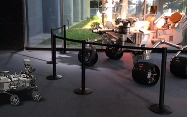 A 3D, augmented reality model of NASA's Curiosity rover shares a scene with a real life model of the rover in a view taken with NASA's Spacecraft 3D app.