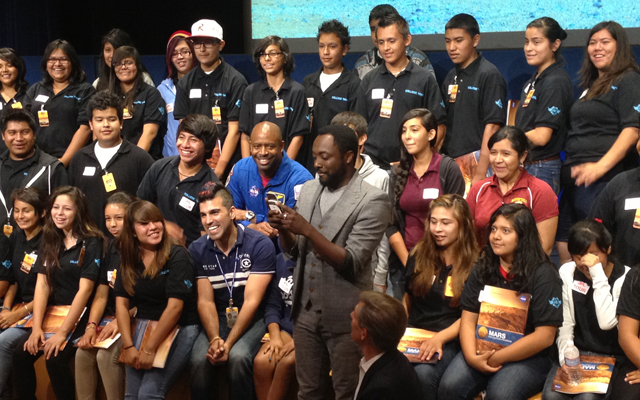 With students and NASA space shuttle astronaut Leland Melvin looking on, musical artist will.i.am posts a tweet soon after his song "Reach for the Stars" was beamed back from the Curiosity Mars rover and broadcast to a live audience at NASA's Jet Propulsion Laboratory in Pasadena, Calif.