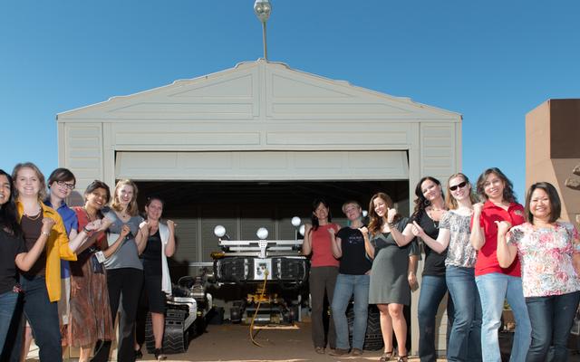 This is a picture of some of the women working on the Curiosity rover posing with Curiosity's mobility double, "Scarecrow," used to test drive under different soil conditions in the JPL "Mars Yard."