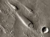 In Ares Vallis, teardrop mesas extend like pennants behind impact craters, where the raised rocky rims diverted the floods and protected the ground from erosion.