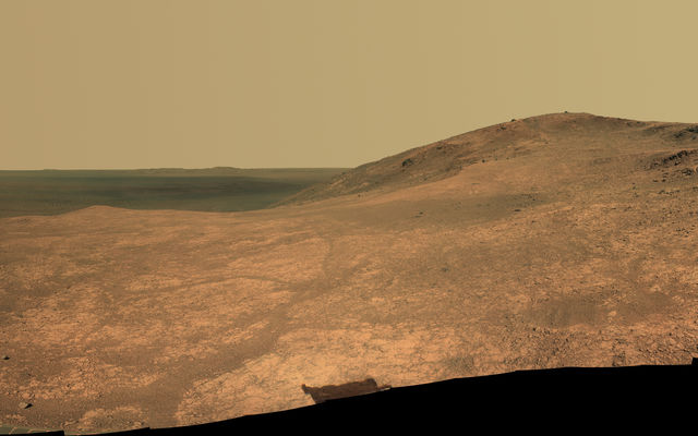 "Marathon Valley" on Mars opens to a view across Endeavour Crater in this scene from the Pancam of NASA's Mars rover Opportunity. The scene merges many exposures taken during April and May 2016. The view spans from north (left) to west-southwest. Its foreground shows the valley's fractured texture.