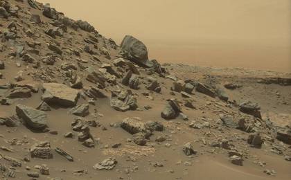 The rim of Gale Crater is visible in the distance, through the dusty haze, in this Curiosity view of a sloping hillside on Mount Sharp