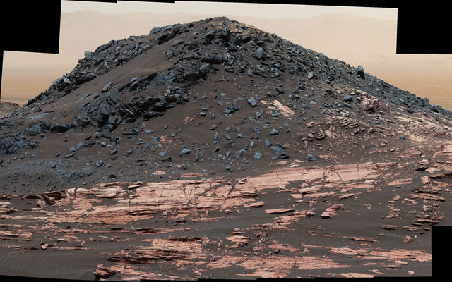 This view from the Curiosity Mars rover's Mastcam shows a dark mound, called "Ireson Hill," which rises about 16 feet above redder layered outcrop material on lower Mount Sharp, Mars, near a location where Curiosity examined a linear sand dune in February 2017.