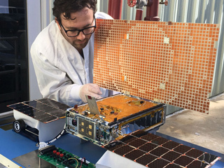 Engineer Joel Steinkraus tests the solar arrays on one of the Mars Cube One 