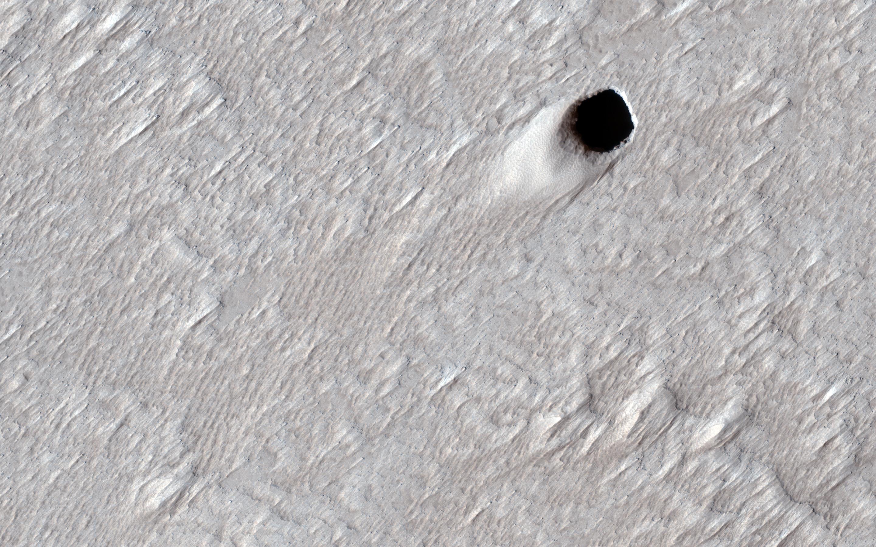 This image acquired on August 16, 2020 by NASAs Mars Reconnaissance Orbiter, shows the ceiling of a lava tube has collapsed in one spot and made this pit crater.