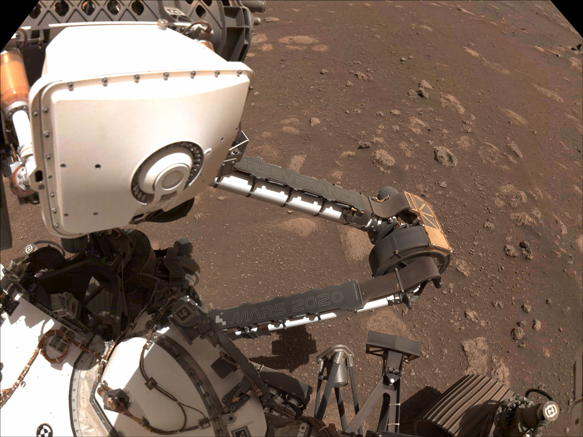 An image taken on Mars of the Perseverance rover’s robotic arm bent to reveal two name plates. One name plate reads "Perseverance" and the other reads "Mars 2020."
