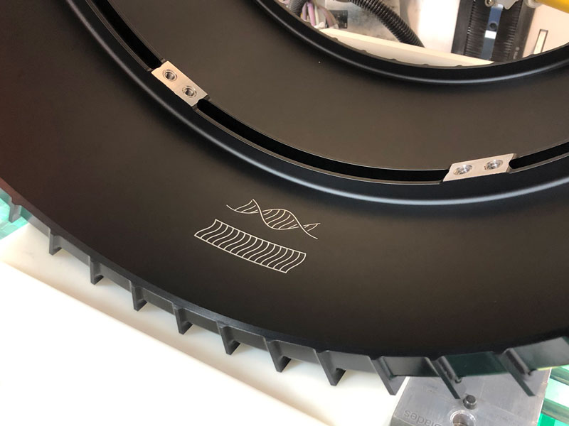 Photo of a rover wheel with etched illustration inside, featuring two sets of rover wheel tracks, one straight and one twisted.