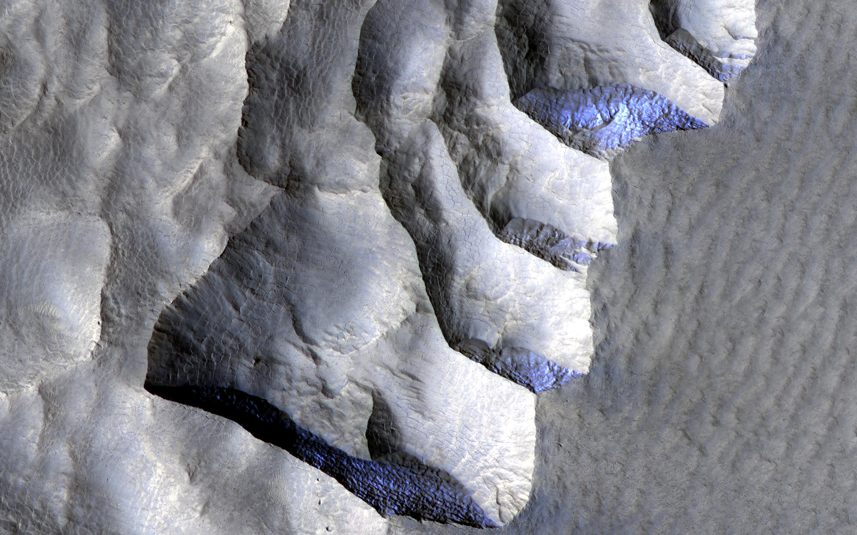 This image acquired on November 2, 2021 by NASAs Mars Reconnaissance Orbiter, shows an area on the western edge of Milankovic Crater on Mars, that has a thick deposit of sediment covering a layer rich in ice.