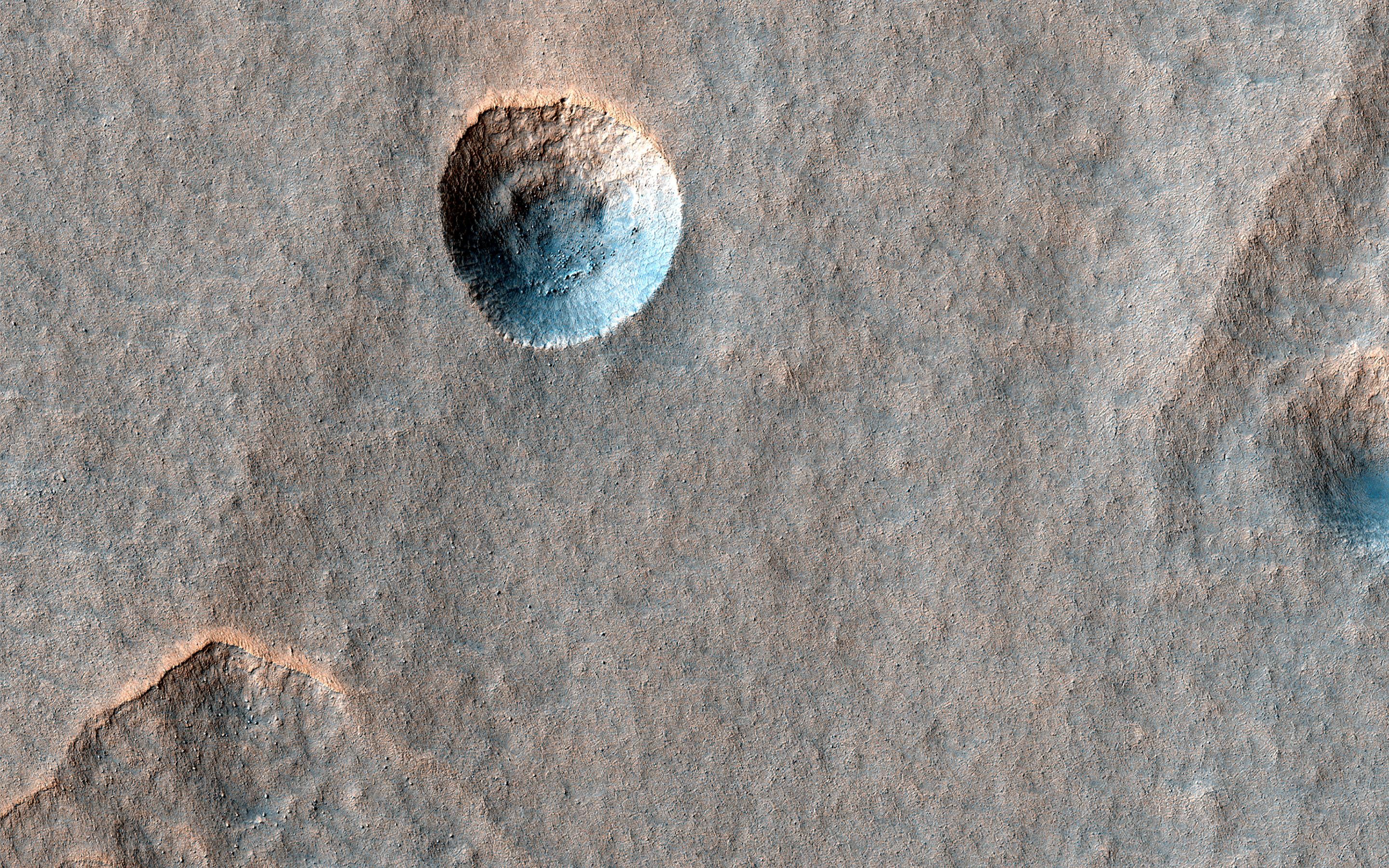 This image acquired on July 8, 2022 by NASAs Mars Reconnaissance Orbiter shows what appears to be a slightly expanded crater in a field of scalloped depressions. Its possible that it will evolve over time to look more like the scallops.