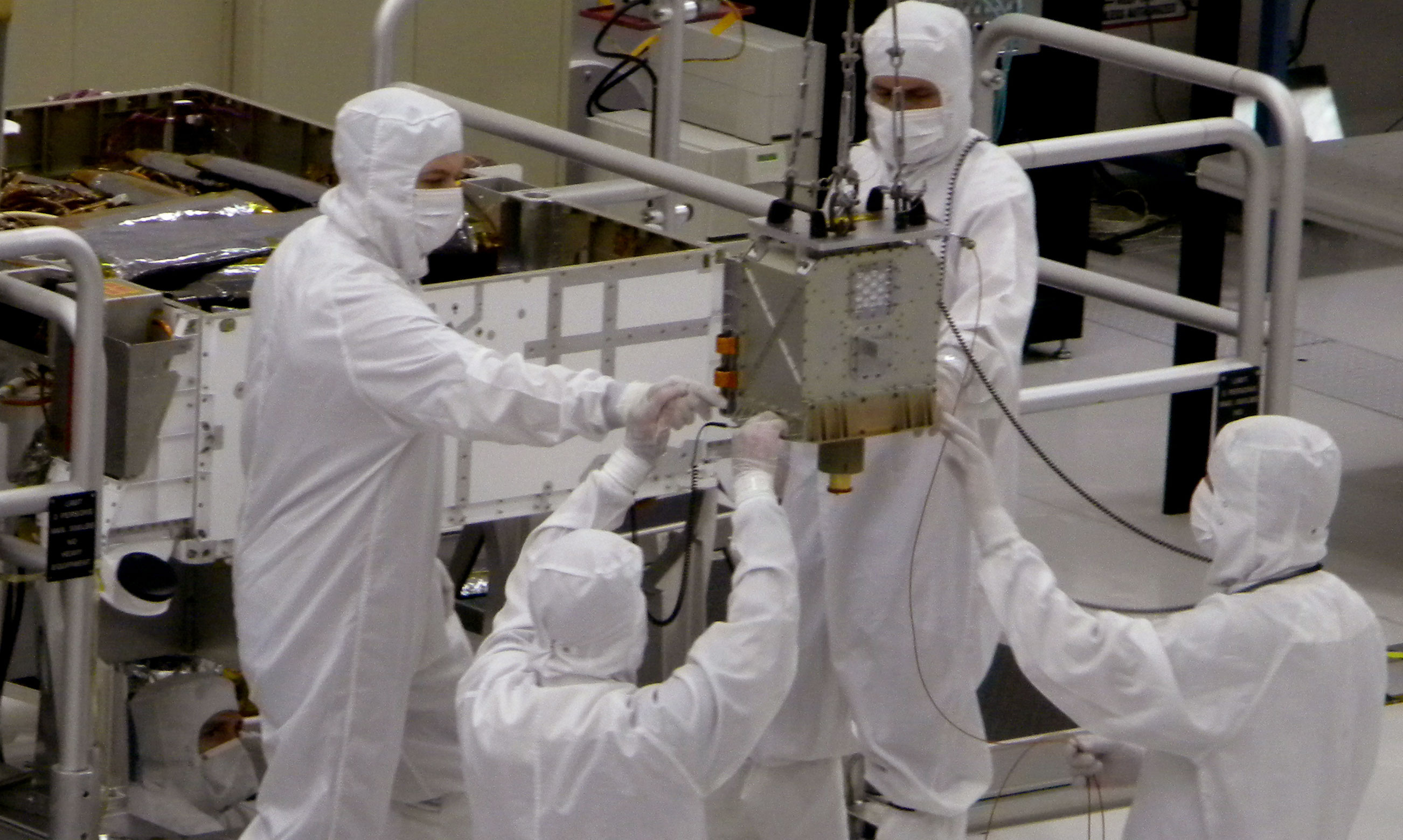 Members of NASA's Mars Science Laboratory team carefully steer the hoisted Chemistry and Mineralogy (CheMin) instrument during its installation into the Mars rover, Curiosity.