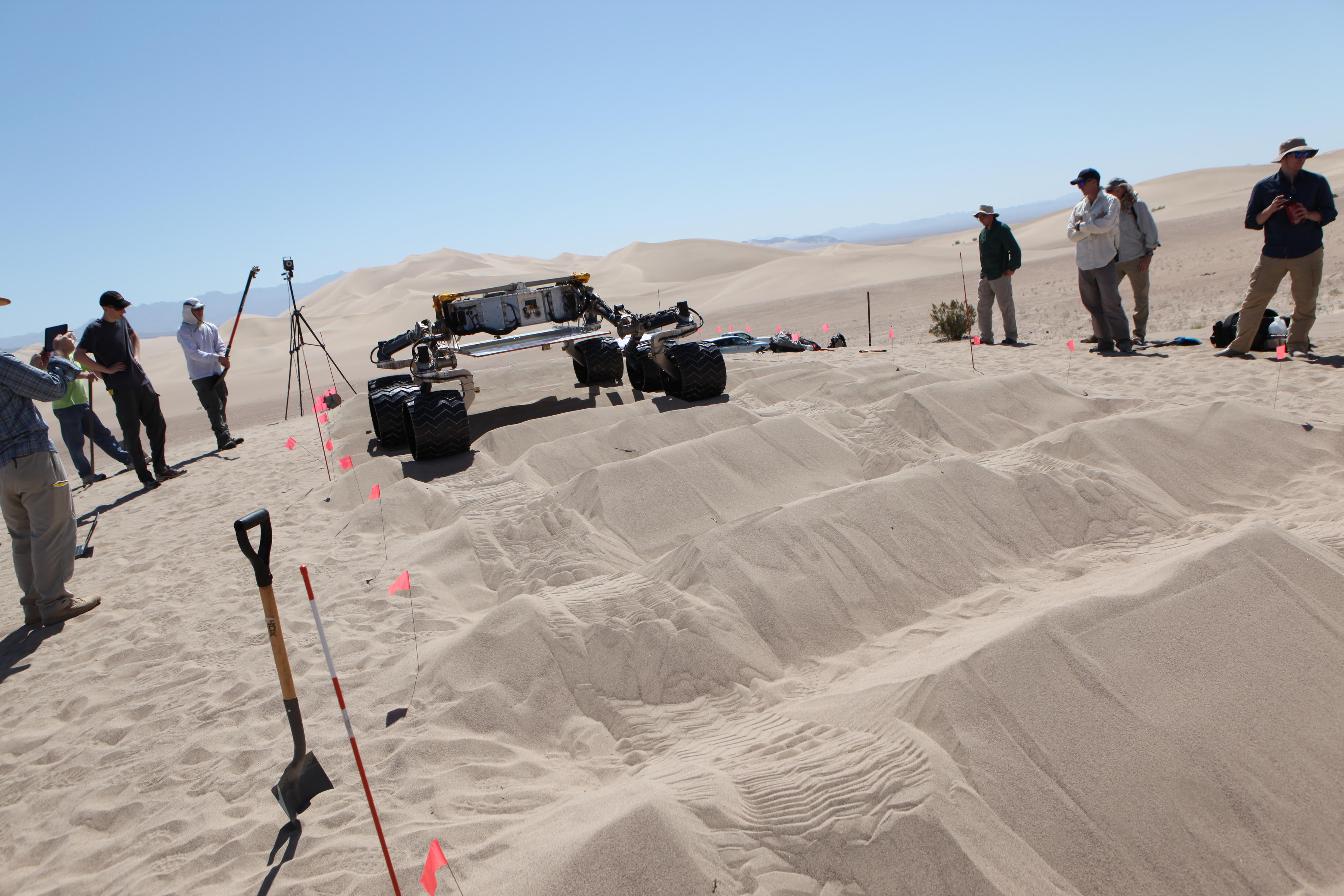sand dune, mars rover, wheel, Dumont, Scarecrow, test - Several engineers flank the Scarecrow mobility rover on both sides as the rover drives over a sand dunes obstacle course.