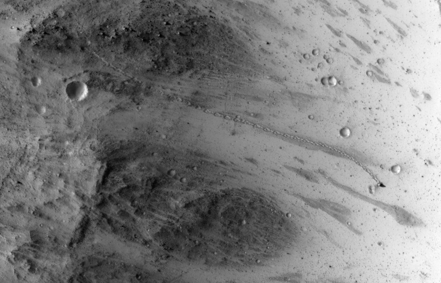 A path resembling a dotted line from the upper left to middle right of this image is the track left by an irregularly shaped, oblong boulder as it tumbled down a slope on Mars before coming to rest in an upright attitude at the downhill end of the track.