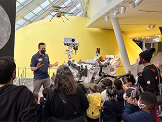 This image shows members of the public meeting with NASA Mars team members to see the Perseverance rover and Ingenuity helicopter models up close during a "Roving With Perseverance" tour stop at the Adler Planetarium in Chicago.